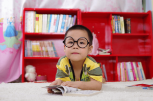 child wearing glasses reading a comic book